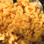 delicious southern macaroni and cheese being stirred in a metal pot