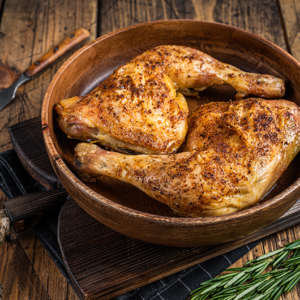 BBQ Grilled chicken legs in a wooden plate with herbs. wooden background