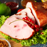 cooked ham on a wooden plate surrounded by veggies