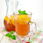 Lemonade with cherry in wineglass and pitcher on board