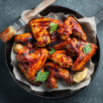 Baked chicken wings in barbecue sauce with sesame seeds and parsley