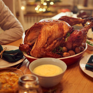 Happy African American woman enjoying in conversation with her friend while gathering for Thanksgiving at dining table.