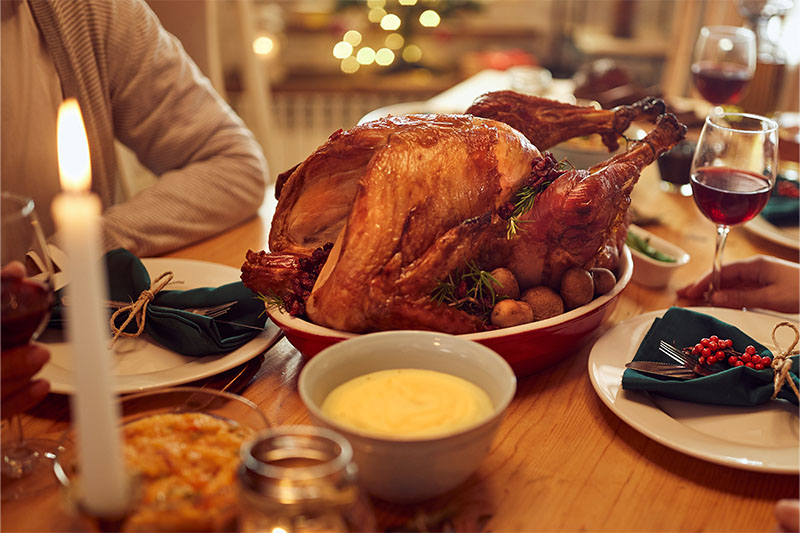 Turkey Day Happy African American woman enjoying in conversation with her friend while gathering for Thanksgiving at dining table.